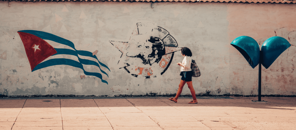 Frau auf Straße von Havanna, Kuba - zwischen Telefonbox und kubanischer Flagge