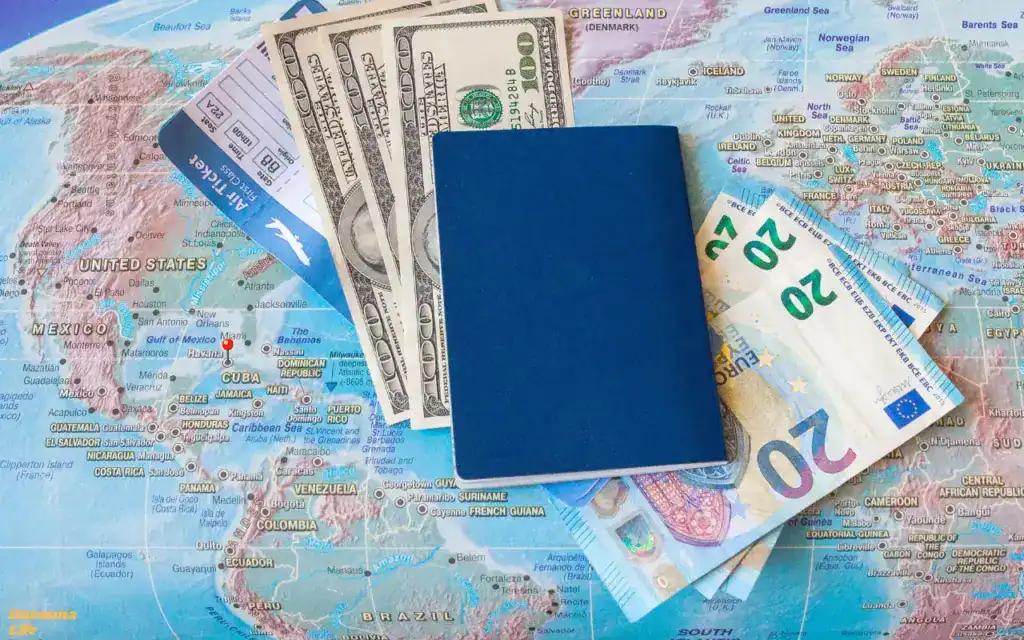 Auf einer Weltkarte liegen in der Mitte ein Pass, sowie Dollar und Euro Scheine und ein Flugticket - Welche Währung braucht man auf Kuba?