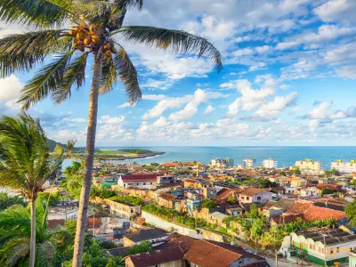 Blick auf Baracoa in Kuba mit Palmen, bunten Dächern und Meer im Hintergrund – die älteste Stadt des Landes inmitten tropischer Natur.