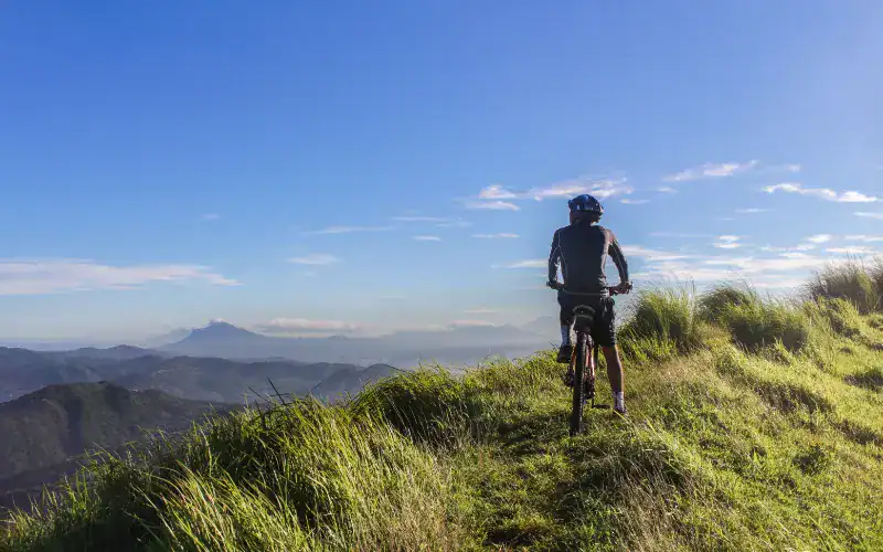 Radfahrer auf einem Hügel mit Blick über Berge und Täler.